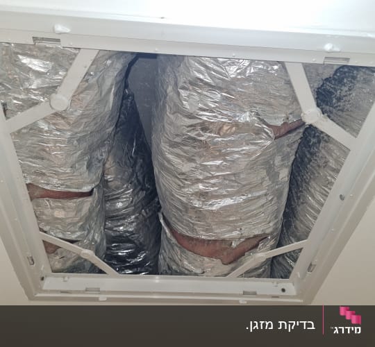 צינורות מיזוג אוויר מכוסים בנייר כסף בתקרה